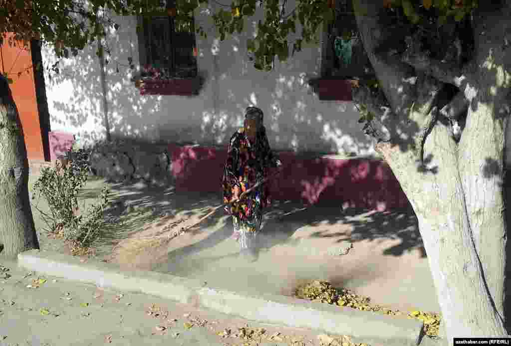 Bir garryja aýal öz öýüniň töweregini süpürýär