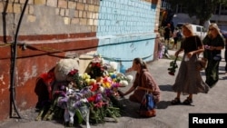 Femeile depun flori la un memorial improvizat lângă un bloc unde ieri 22 de locatari au fost uciși de un atac cu rachete rusești.