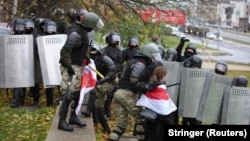 Riot police detain protesters carrying the red-and-white flag of the Belarusian opposition on November 8 in Minsk.