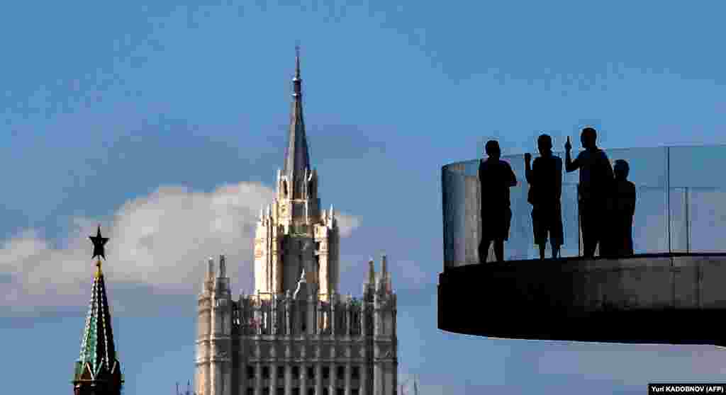 People stand on a bridge at Zaryadye park with a Stalin-era skyscraper and the Kremlin&#39;s tower in the background in central Moscow. (Yuri Kadobnov/AFP)