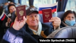 Жители Донецка показывают свои российские паспорта в автобусе, который должен доставить их на избирательный участок в Ростовской области для голосования на выборах в Госдуму. 17 сентября 2021 года