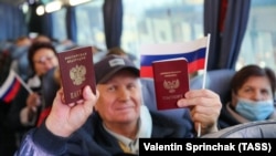 Жители Донецка показывают свои российские паспорта в автобусе, который должен доставить их на избирательный участок в Ростовской области для голосования в выборах в российскую Госдуму. 17 сентября 2021 года