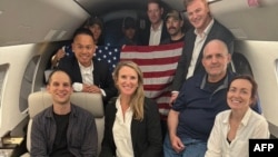 In this image released by the U.S. government, Wall Street Journal reporter Evan Gershkovich (left), former U.S. Marine Paul Whelan (second from right), and RFE/RL journalist Alsu Kurmasheva (right) are seen on a plane after their release from Russia on August 1.