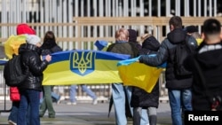 Демонстранты развернули украинский флаг во время переговоров о мире в Украине. Женева, 17 февраля 2026 года