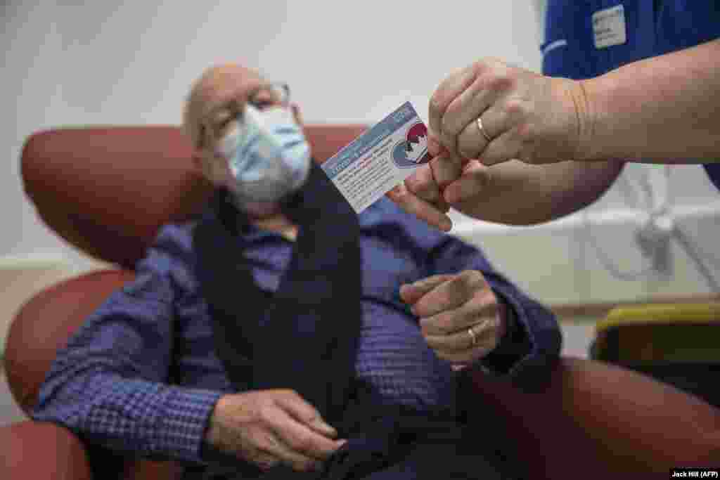 Медицинската сестра Наоми Волш (десно) му ја покажа на Роџер Шоу (87), неговата картичка за вакцинирање, откако прими вакцина&nbsp; во болницата Royal Free во Лондон&nbsp;