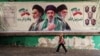 A woman in Tehran walks past a banner depicting late Iranian Supreme Leader Ruhollah Khomeini (left), Iranian Supreme Leader Mojtaba Khamenei (center), and Supreme Leader Ayatollah Ali Khamenei, who was killed in an air strike earlier this year. 