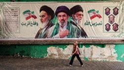 A woman in Tehran walks past a banner depicting late Iranian Supreme Leader Ruhollah Khomeini (left), Iranian Supreme Leader Mojtaba Khamenei (center), and Supreme Leader Ayatollah Ali Khamenei, who was killed in an air strike earlier this year. 