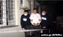 Georgian ex-President Mikheil Saakashvili is escorted by police officers as he arrives at a prison in Rustavi on October 1.