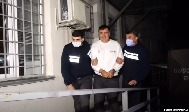Georgian ex-President Mikheil Saakashvili is escorted by police officers as he arrives at a prison in Rustavi on October 1.