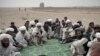 Tribal leaders listen to a U.S. Marine as they gather in the desert for a meeting in Sistani, Helmand Province.