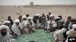 Tribal leaders listen to a U.S. Marine as they gather in the desert for a meeting in Sistani, Helmand Province.