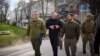 Ukrainian President Volodymyr Zelenskiy (right) walks along a street as he visits Kherson on March 23.
