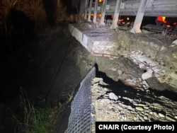 Detaliu cu grinda de consolă care susține drumul și alunecarea de teren de sub grindă, suficientă pentru a susține traficul. Pentru a evita vibrațiile și tendința vehiculelor de a se apropia de acostament, au fost montate balize, pentru că vibrațiile ar putea agrava alunecarea.