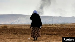 A female Kurdish refugee tries to call relatives who are still trapped in Kobani as thick smoke rises from the Syrian town during heavy fighting between Islamic State militants and Kurdish peshmerga forces on October 27.