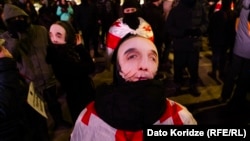 Protesters in Tbilisi wear masks in defiance of a new law banning face-coverings in Georgia.