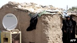 A TV satellite dish sits next next to a makeshift home in Baghdad's al-Dora slum (file photo)