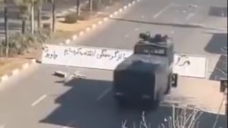 یک خودرو آب‌پاش نیروی ضدشورش پلیس در شهر شیراز در حال عبور از مانعی که معترضان در خیابان برپا کرده بودند