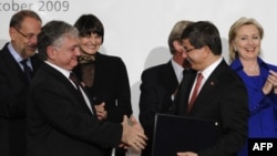 Switzerland -- Turkish Foreign Minister Ahmet Davutoglu (2ndR) and his Armenian counterpart Eduard Nalbandian shake hands as they hold signed Turkish-Armenian protocols, Zurich, 10Oct2009.