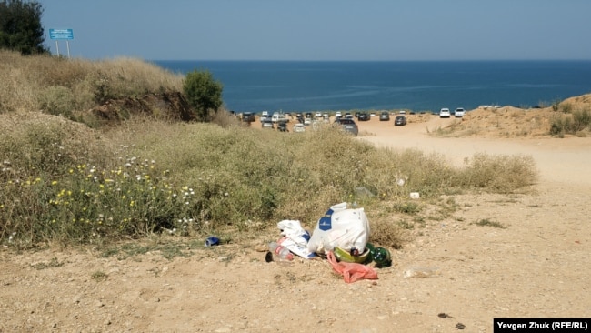 Отдыхающие выбрасывают мусор и ставят автомобили рядом с пляжем в Немецкой балке. Севастополь, июль 2021 года