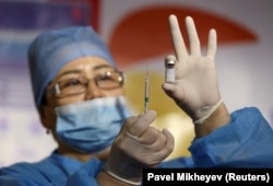 Медработник показывает шприц и флакон с вакциной QazCovid-in против коронавирусной болезни в пункте вакцинации, расположенном в торгово-развлекательном центре в Алматы. Казахстан, 27 апреля 2021 года.