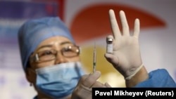 Медицинский работник показывает шприц и флакон с вакциной QazCovid-in против коронавирусной болезни (COVID-19) в пункте вакцинации, расположенном в торгово-развлекательном центре в Алматы, Казахстан, 27 апреля 2021 года. 