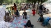Afghan people rest on tents and blankets as they seek to receive asylum from the United Nations High Commissioner for Refugees in Islamabad on May 9, 2022. 