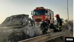 Emergency workers remove a car which exploded into flames after Iranian police reportedly opened fire on it. Three Afghan migrants died in the incident. 