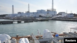 In a photo from April, a U.S. military barge delivering pure water (bottom) floats near the quay with the crippled Fukushima Daiichi Nuclear Power Plant in the background.