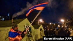 Az ellenzék egyik szimpatizánsa egy örmény zászlóval a Nikol Pasinjan örmény miniszterelnök lemondását követelő tüntetésen Jerevánban, Örményországban, 2021. február 25-én.