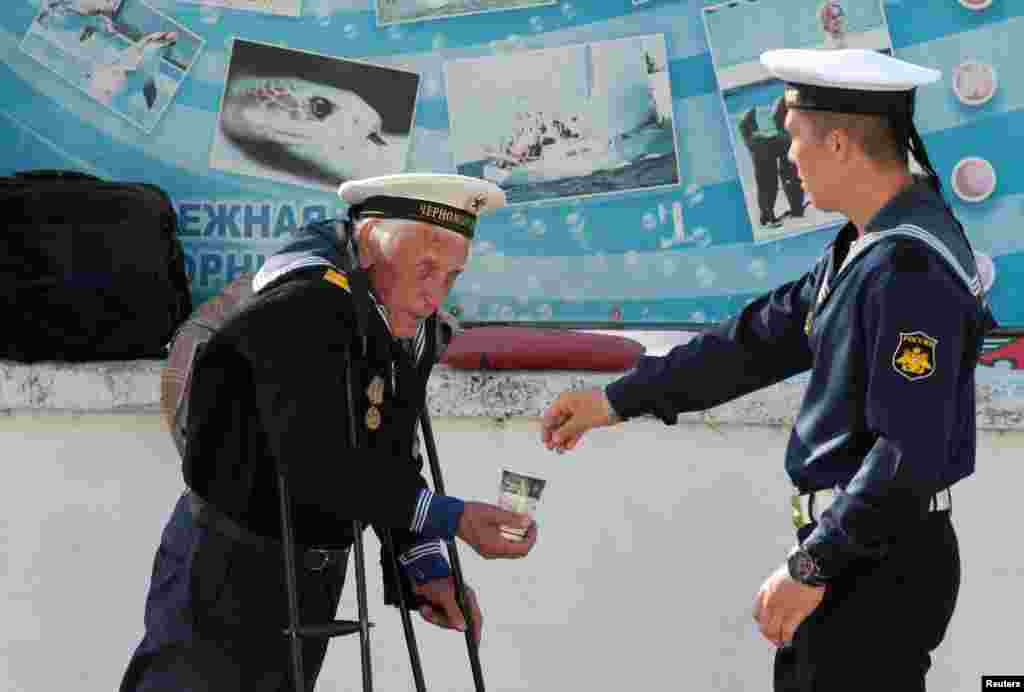 A Russian Navy serviceman gives alms to a beggar on an embankment of the Black Sea port of Sevastopol in the annexed Crimea Peninsula. (Reuters/Pavel Rebrov)