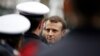 French President Emmanuel Macron speaks with policemen during a commemorative ceremony to mark the third anniversary of the attack on Charlie Hebdo magazine in Paris. 