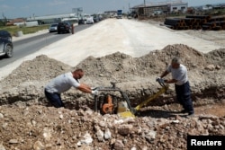 Dy persona duke punuar në një rrugë në Vushtrri më 18 qershor 2024. Ditëve të fundit, Kosova është përballur me tempatura mbi 35 gradë Celsius.