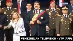 Венесуэланын телеканалы көрсөткөн видеодон алынган сүрөт. Президент Мадуро жубайы менен ортодо турат. 4-август, 2018-жыл. 