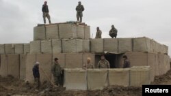 Afghan soldiers stand at a checkpoint in Kunduz where clashes took place between Taliban and Afghan forces amid a recent flare-up in deadly violence.