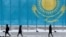 Люди на улице в Астане на фоне флага Казахстана
