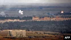 Smoke billows in the background as Syrian regime fighters advance to retake the ancient city of Palmyra from Islamic State fighters on March 2.