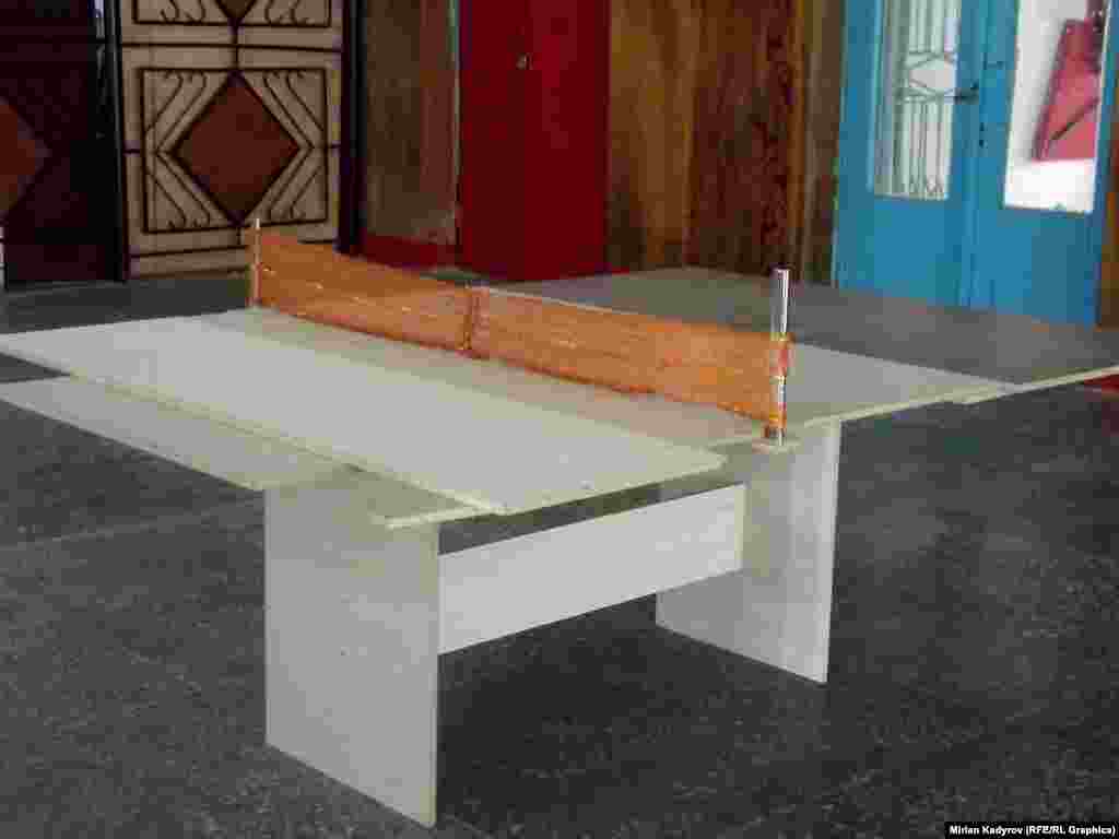 Рейсин күткөндөр колго жасалган столдо пинг-понг ойношот.