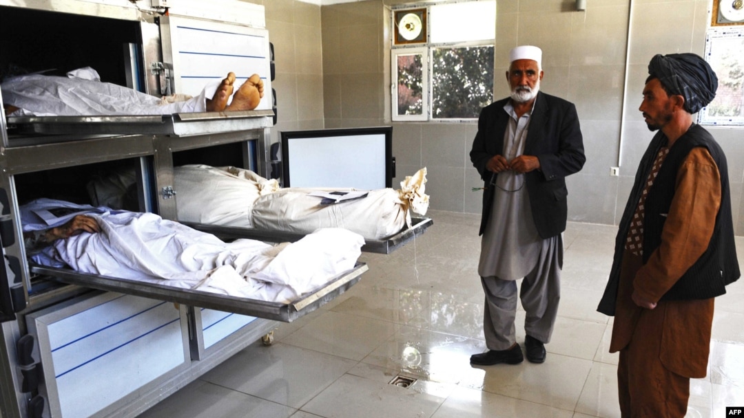Men stand next to the bodies of the workers who were killed by Taliban insurgents in the western Herat Province on August 26.