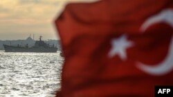 A Turkish flag flies on a ferry as Russian warship, the BSF Saratov 150, sails through the Bosphorus off Istanbul en route from the Black Sea to the eastern Mediterranean late last year. 