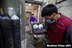 Dy punëtorë shëndetësorë transportojnë bombola të oksigjenti në një spital në Srinagar të indisë. 25 prill, 2021.
