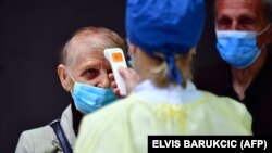 Zdravstveni radnici u BiH provjeravaju temperaturu građanima prije ulaska u punkt za vakcinaciju u Sarajevu, 21. april 2021. godine