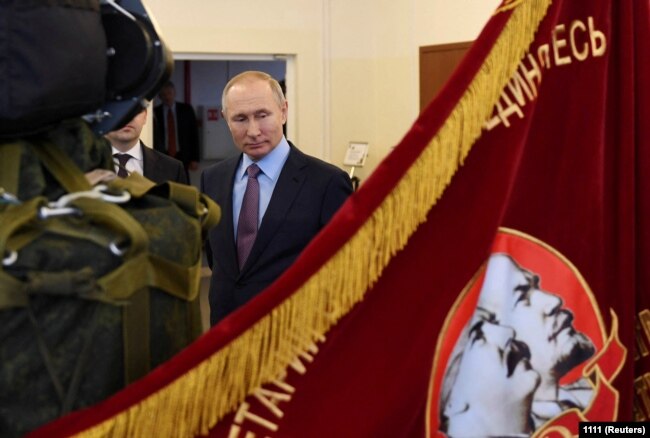 Vladimir Putin near a flag depicting Soviet leaders Vladimir Lenin and Joseph Stalin at a Russian military industrial complex factory in the city of Ivanovo. March 2020