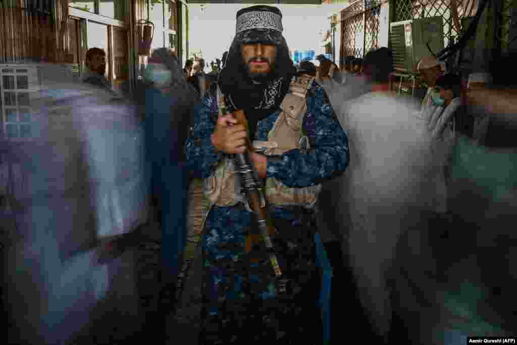 A Taliban fighter stands guard as people move past him at a market in Kabul.