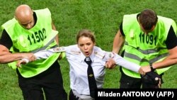 A member of Pussy Riot is apprehended by stewards after running onto the field at the final of the World Cup football match between France and Croatia in Moscow on July 15.