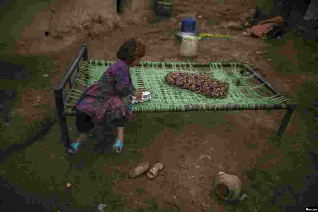 An Afghan girl, whose family fled the Soviet-led war in Afghanistan, plays with a toy bus beside her makeshift shelter in a slum on the outskirts of Islamabad, Pakistan. (Reuters/Zohra Bensemra)