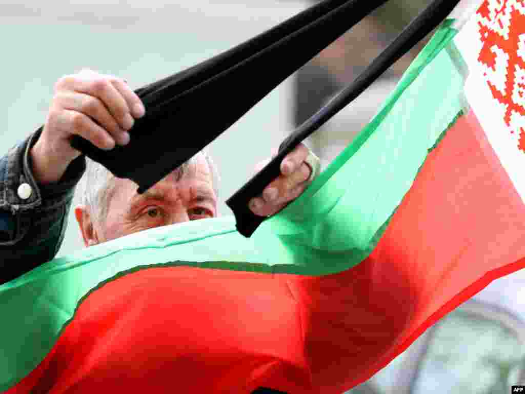 A man straightens mourning ribbons on the Belarusian flag in Minsk on April 13, two days after the blast that killed at least 13 people. Photo by Alexey Gromov for AFP