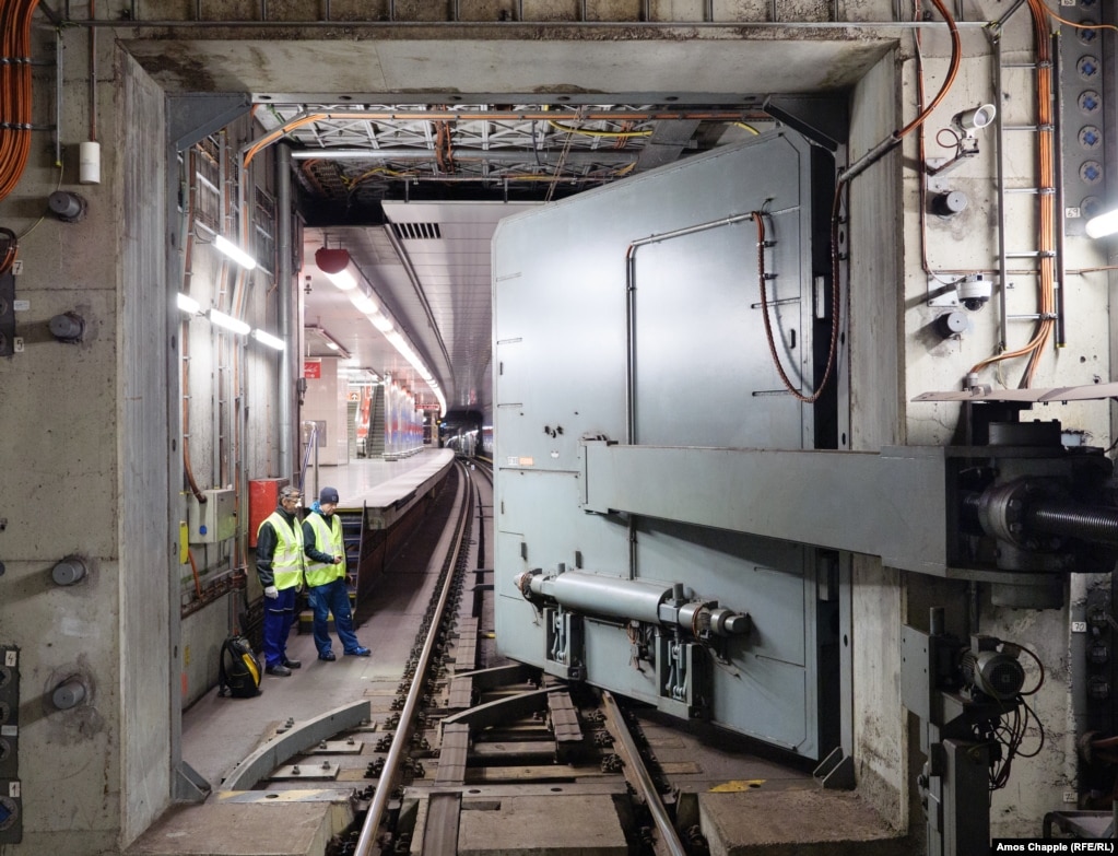 Inxhinierët duke shikuar ndërsa dera rezistente ndaj shpërthimeve me mbyllje hermetike, lëviz mbi shinat e metrosë. Sistemi Mbrojtës i Metrosë u ndërtua në rrjetin e metrosë së Pragës duke filluar nga viti 1974, kur hija e luftës bërthamore po përndiqte Evropën.