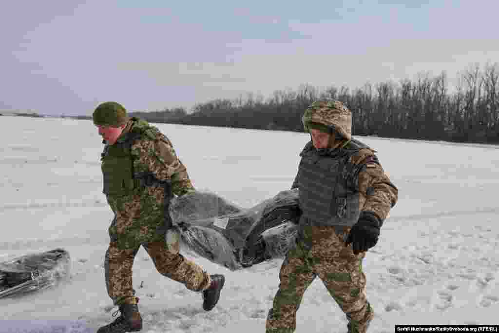 Військові несуть мотки путанки – тонкого сталевого дроту-сітки для будування інженерних загороджень