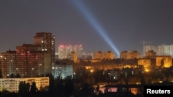 Ukrainian service personnel use searchlights to look for drones in the sky over the city center during a Russian drone strike in Kyiv on September 9.