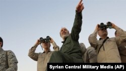 Iran's army chief of staff Maj. Gen. Mohammad Bagheri (L) looks into binoculars, as he and other senior officers from the Iranian military visit a frontline in the northern province of Aleppo, October 20, 2017